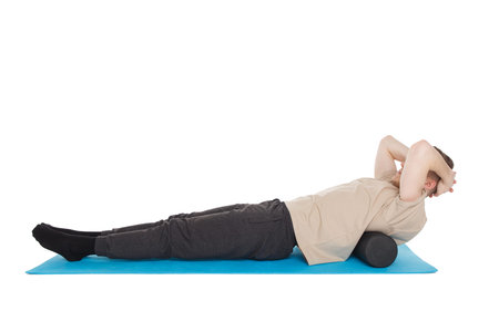 Handsome man shows exercises using a foam roller for a myofascial release massage of trigger points....