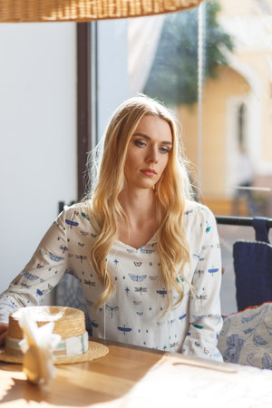 Young pretty woman wearing in white dress resting in cafe