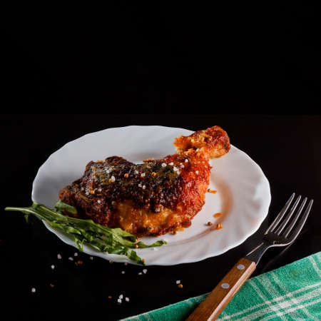Fried chicken leg on a white plate served on a black backgroundの写真素材