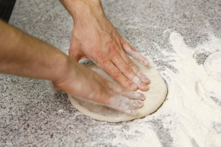 Making dough by male hands on table background. Pizza maker prepares a pizza dough.