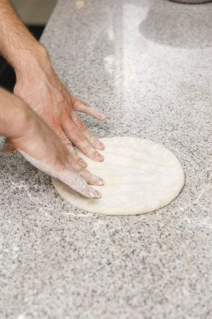 Making dough by male hands on table background. Pizza maker prepares a pizza dough.