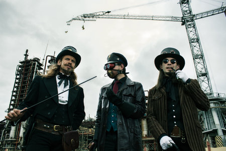 Three mans in steampunk style discuss standing against the industrial background