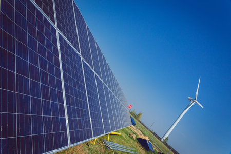 Green alternative energy and environment protection ecology concept - solar battery panels and wind generator turbines against blue skyの写真素材