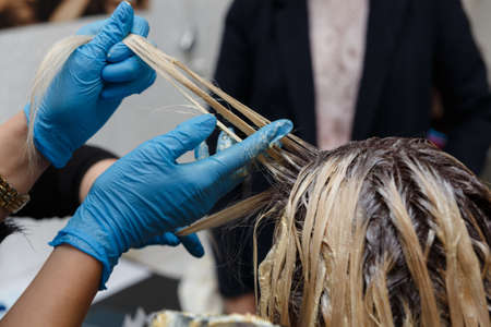 Hairdresser salon. Hair coloring in process. Woman dyeing hairs.の写真素材