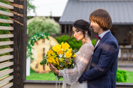 Newly married posing near by luxurious wooden mansion on wedding ceremonyの写真素材