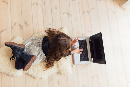 Small cute brunette caucasian baby laying on floor on light artificial animal skin and watching...