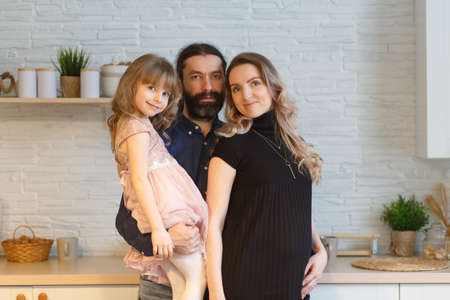Family on the light kitchen. Pregnant woman with her husband and little daughter.の写真素材