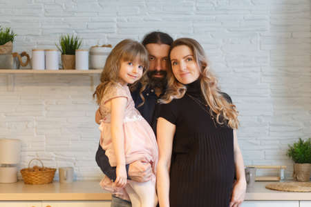 Family on the light kitchen. Pregnant woman with her husband and little daughter.の写真素材