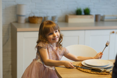 Small girl sets the table for a meal at a family dinner.の写真素材