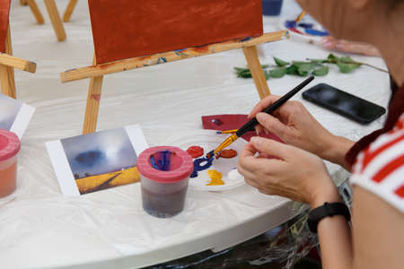 Closeup of female artist hand paint a picture on a palette at workshop, close up top view, selective focus, tonedの写真素材