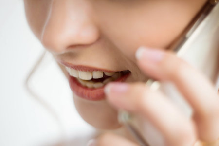 Close-up of the mouth and lips of a woman talking on a smartphone on a white background. White...