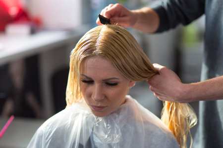 Grodno, Belarus - October 20, 2016: Keune brand technologist Artem Raychuk dyes the hair of a model on advertising workshop with the participation in the beauty salon Kolibri.のeditorial素材