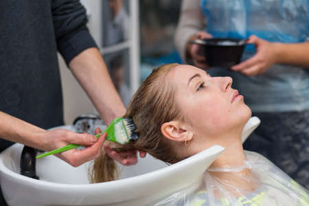 Grodno, Belarus - October 20, 2016: Keune brand technologist Artem Raychuk dyes the hair of a model on advertising workshop with the participation in the beauty salon Kolibri.のeditorial素材