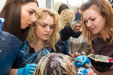 Grodno, Belarus - October 20, 2016: Participants of the seminar dye the hair of a model on advertising workshop of Keune brand in the beauty salon Kolibri.のeditorial素材