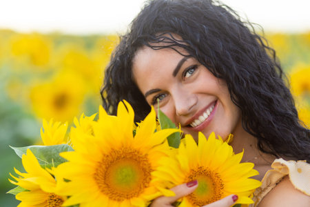 Portrait of a beautiful smiling dark-haired woman with bouquet of sunflowersの写真素材