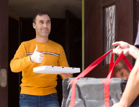 food delivery, mail and people concept. A satisfied customer received a pizza and gives a thumbs up.の写真素材
