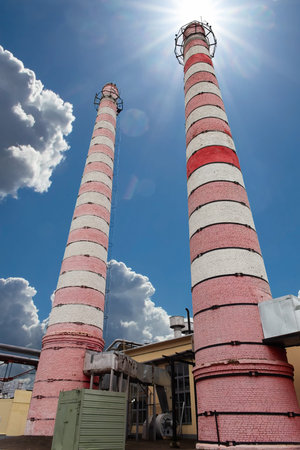 Industrial plant chimneys. District heating plant exterior with industrial chimneys against the sun...