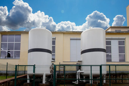Liquified nitrogen in two storage tanks outside industrial building. The tanks are fenced with a...