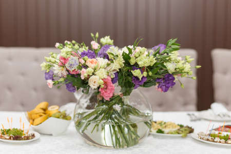 Festive table served with bouquet of wild roses in a vase, appetizers and salads for the holiday.の写真素材