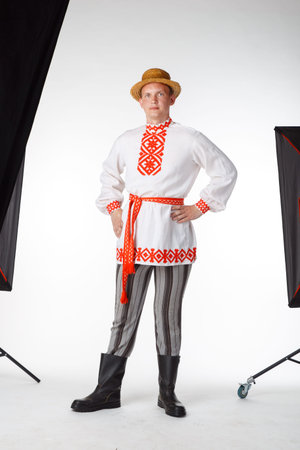 Beautiful young man in Belarusian national costume posing in a studio during the photo sessionの写真素材
