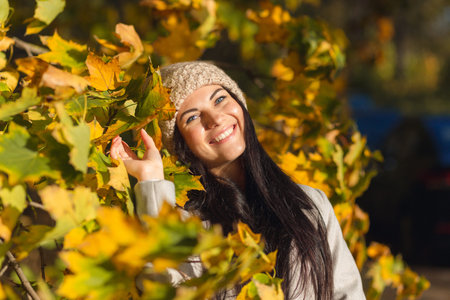 Portrait of a joyful young woman enjoying in the autumn park. Beautiful brunette girl in autumn grey...