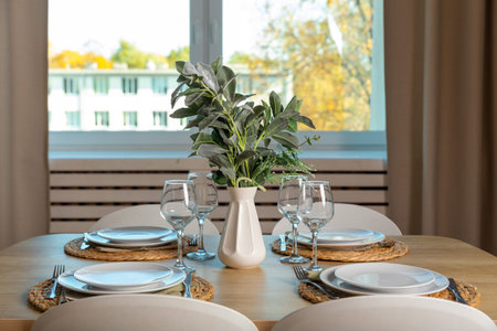 Breakfast setup on wooden table with nice vase and modern chair. A table set for forur people family.の写真素材
