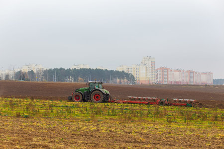 A tractor with a large double plow plows a field in autumn.