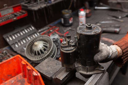 Mechanic with dirty gloves repair broken starter on car. Automotive service.の写真素材