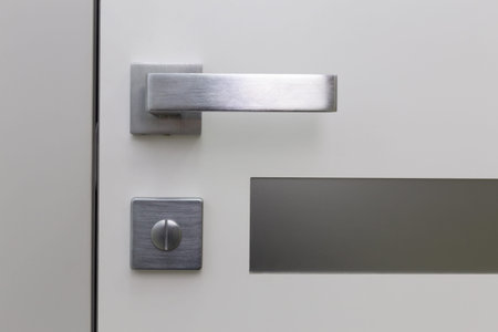 Metal handle with lock on plastic entrance door. Close-up photo of architecture detail. Interior fragment as geometrical conceptual background.の写真素材