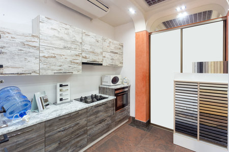 Kitchen interior designed in beige color and decorated in wood with stone counter in furniture salon.の写真素材
