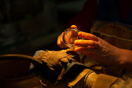 Unrecognizable woman decorating glass in manufacture with diamond circle. Applying the pattern...