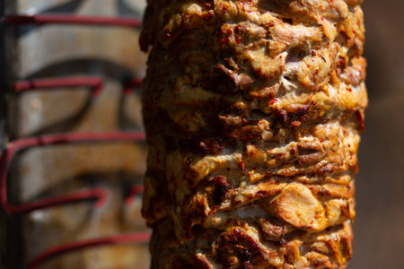 Close up shot of stacked meat roasting to be used in preparation of traditional Greek dish gyros or Turkish durum doner. Copy space with blurred hot electrical oven.の写真素材