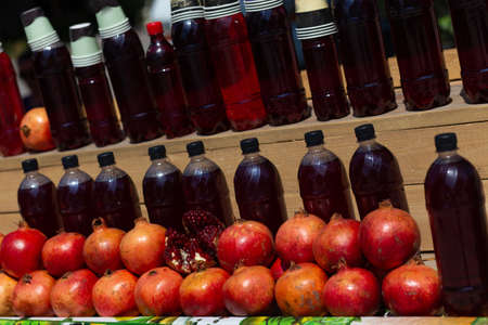 Fresh pomegranates on the market. Pomegranates for juice on the counter of the fruit street market. Freshly squeezed pomegranate juice, bottled in plastic bottles.の写真素材