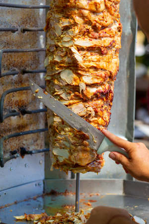 Chef cutting with doner knife Traditional Turkish Doner Kebab meat. Shawarma or gyros. Turkish, greek or middle eastern arab style chicken doner kebab food.の写真素材