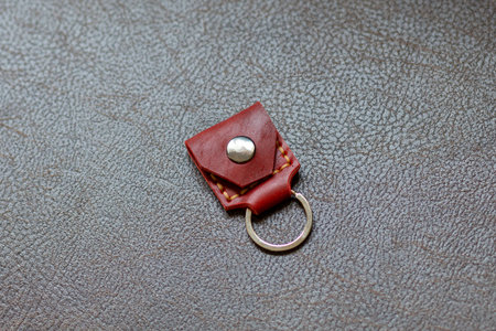 Orange leather key strap with iron ring for mounting on a belt on a leather background. Back side.の写真素材