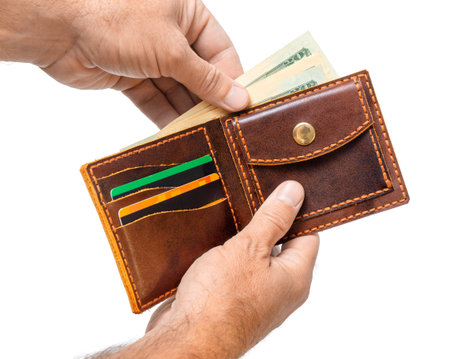 A man is holding an open brown wallet with money and credit cards isolated on a white background...