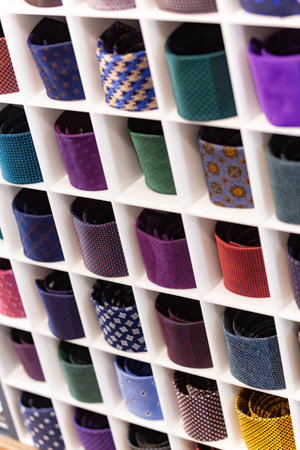 Showcase with multicolored ties. View of different colors ties in showcase. Showcase of rolled neckties at store. Twisted neckties are beautifully stacked in cells. Selective focus.の写真素材