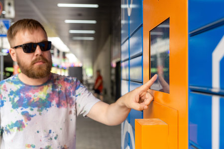 Man enters parcel code on screen and picks up parcel from automated postal machine. Man holds...