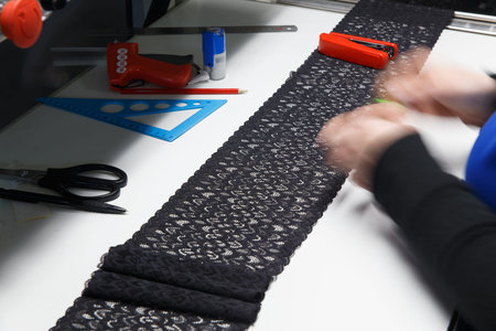 A female employee performs visual quality control of the lace ribbon before using it in the...