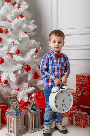 Small cute boy casual dressed standing in white room among christmas decorations. Christmas photo of kid in decorated fo christmas room. New Year concept.の写真素材