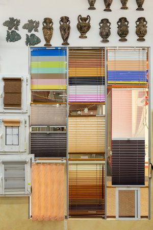 Samples of blinds for windows in the store. Plastic blinds, pleated, roll-up and day-night curtains in store.の写真素材