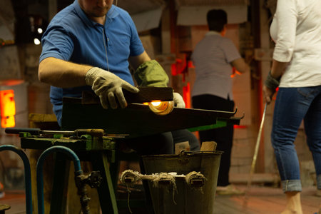 A glass blower is working on the manufacture of glass vases and glasses. Trimming excess glass from the product Up to 20 workers can be involved simultaneously in the production of particularly complex products.の写真素材
