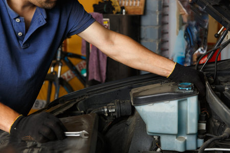 Car service, repair, maintenance and people concept - auto mechanic looking for a malfunction in the...