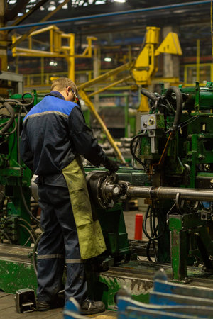 Worker on workplace of an employee of a plant for the production of cardan shafts. A machine for...