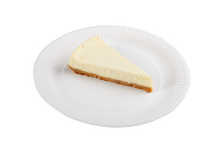 A piece of cheesecake on a paper plate isolated on white background. Top view.の写真素材