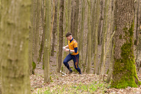 Grivki, Belarus - 26 March, 2023: Strong caucasian teenage boy wearing sportswear running through a forest during exercise in outdoor orienteering Grodno Forest Day. Belarus, hobby sport.のeditorial素材
