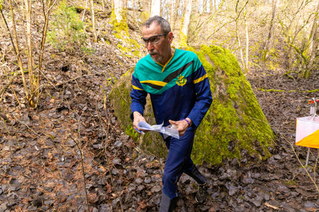 Grodno, Belarus - 25 March, 2023: Strong elderly caucasian man wearing sportswear running through a forest during exercise in outdoor orienteering Grodno Forest Day. Belarus, hobby sport.のeditorial素材