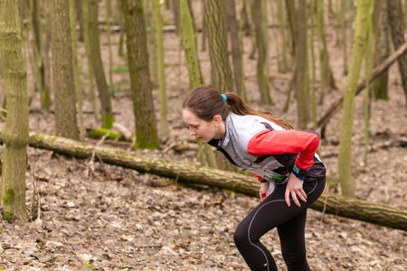 Grodno, Belarus - 26 March, 2023: Strong caucasian young woman wearing sportswear running through a forest during exercise in outdoor orienteering Grodno Forest Day. Belarus, hobby sport.のeditorial素材