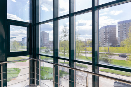 Street view on a sunny summer day from the landing of the stairwell with panoramic glazing. An...