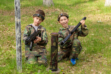 Two boys weared in camouflage playing laser tag in special forest playground. Laser Tag is a command military tactical game using safe laser weapons and sensors that record hits.の写真素材